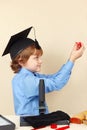 Little professor in academic hat conducts scientific research with microscope Royalty Free Stock Photo