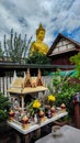 Little protective spirits house in Bangkok beside big golden Buddha statue