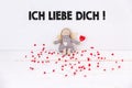 Little puppet with red hearts sitting on white background with `Ich liebe dich` text. Tranlation: `I love you` Royalty Free Stock Photo