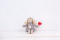 Little puppet with a red heart sitting on a wooden white background