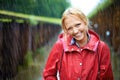 A little rain is quite nice. Gorgeous young blonde woman wearing a red raincoat in the rain outdoors on a country road. Royalty Free Stock Photo