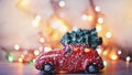Little red car toy carrying Christmas tree in snow and bokeh christmas lights Royalty Free Stock Photo