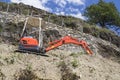 Little red excavator on a mountain with trees