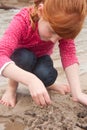 Little red haired girl building a sand castle with wet sand at a Royalty Free Stock Photo