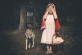 Girl in costume of little red riding hood in forest posing with wolf dog Royalty Free Stock Photo