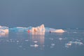 Little red sailboat cruising among floating icebergs in Disko Bay glacier during midnight sun season of polar summer. Greenland Royalty Free Stock Photo