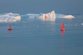 Little red sailboat cruising among floating icebergs in Disko Bay glacier during midnight sun season of polar summer. Greenland Royalty Free Stock Photo