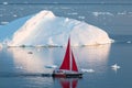 Little red sailboat cruising among floating icebergs in Disko Bay glacier during midnight sun season of polar summer. Greenland Royalty Free Stock Photo