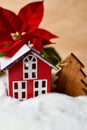 Little red toy house, wooden fir tree and poinsettia.