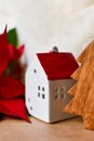 Little red toy house, wooden fir tree and poinsettia.