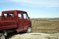 The little red truck stop at the edge of the cliff. Blue sky. View of the road and autumn fields