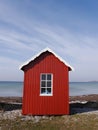 A little red wooden beach hut with blue sea and a windswept blue sky Royalty Free Stock Photo