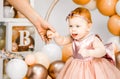 Little redhead baby girl celebrates first birthday anniversary. 1 year family baloons party. Professional photoshoot