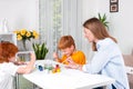 Little redhead boys with a nanny or mother or teacher sit at the table and paint with colors