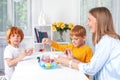 Little redhead boys with a nanny or mother or teacher sit at the table and paint with colors