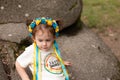 Little redhead preschooler girl with pigtails in national ukrainian folk decoration wreath outdoors