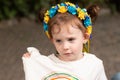 Little redhead preschooler girl with pigtails in national ukrainian folk decoration wreath outdoors