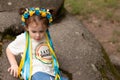 Little redhead preschooler girl with pigtails in national ukrainian folk decoration wreath outdoors