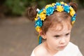 Little redhead preschooler girl with pigtails in national ukrainian folk decoration wreath outdoors