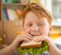 Little redhead schoolboy eating sandwich