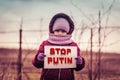 Little refugee girl with a sad look and a poster with the inscription stop putin. Social problem of refugees and internally Royalty Free Stock Photo