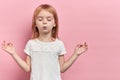 Little relaxed cute girl practicing yoga, isolated on pink