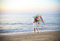 Little running girl with flying kite on beach at sunset Royalty Free Stock Photo