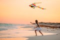 Little running girl with flying kite on tropical beach. Kid play on ocean shore. Royalty Free Stock Photo