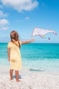 Little running girl with flying kite on tropical beach. Kid play on ocean shore. Royalty Free Stock Photo