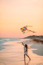 Little running girl with flying kite on tropical beach. Kid play on ocean shore. Royalty Free Stock Photo