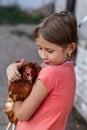Little rural girl with chicken in her arms