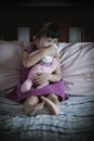 Little sad asian girl sitting on bed. Vignette picture style. Royalty Free Stock Photo