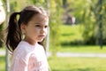 Little sad beautiful girl in a pink t-shirt with pigtails on a walk in the park Royalty Free Stock Photo