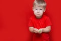Little sad boy kid hold a lot of pills in hands. red t-shirt, red background dangerous concept, tablets and baby Royalty Free Stock Photo