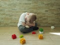Little sad boy sitting on the floor with a block teddy bear Royalty Free Stock Photo