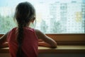 Little sad girl pensive looking through the window glass with a lot of raindrops. Sadness  and loneliness childhood concept image. Royalty Free Stock Photo