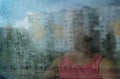 Little sad girl pensive looking through the window glass with a lot of raindrops. Sadness  and loneliness childhood concept image. Royalty Free Stock Photo