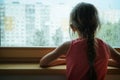 Little sad girl pensive looking through the window glass with a lot of raindrops. Sadness and loneliness childhood concept image. Royalty Free Stock Photo