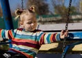 Little sad girl on a swing in the park. Royalty Free Stock Photo