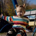 Little sad girl on a swing in the park. Royalty Free Stock Photo