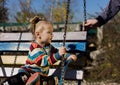 Little sad girl on a swing in the park. Royalty Free Stock Photo