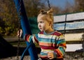 Little sad girl on a swing in the park. Royalty Free Stock Photo