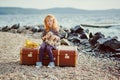 A little sad girl with a toy sitting on a big suitcase near the Royalty Free Stock Photo