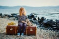A little sad girl with a toy sitting on a large suitcase near th Royalty Free Stock Photo