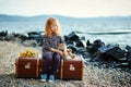 A little sad girl with a toy sitting on a large suitcase near th Royalty Free Stock Photo