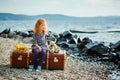 A little sad girl with a toy sitting on a large suitcase near th Royalty Free Stock Photo