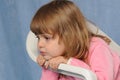 Little sad girl on white chair at studio portrait