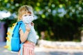 Little sad toddler girl with medical mask against corona virus covid on way to nursery or playschool. Unhappy upset Royalty Free Stock Photo