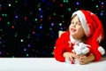 Little Santa Claus with Christmas gifts is smailing. Four year old baby in festive santa costume