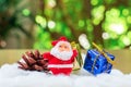 Little santa claus with pine cone and group of giftbox on white cotton with green boken bacjground. Christmas concept